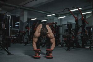 Homem musculoso de 35 anos em posição de treinamento de força em ambiente de academia