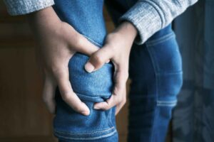 Eletrodos adesivos aplicados sobre o joelho de um paciente durante sessão de estimulação elétrica muscular em clínica de fisioterapia