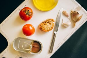 Mesa com alimentos típicos da dieta mediterrânea: azeite, peixes, vegetais frescos e frutas
