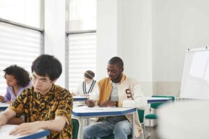 Alunos em sala de exame sentados em carteiras durante prova individual