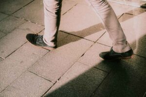 Pessoa caminhando ao ar livre com tênis e rastreador de passos visível no pulso