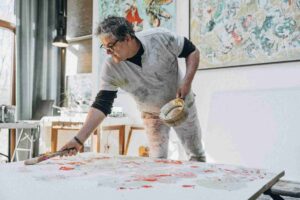 Artista pintando em tela com pincéis durante aula de pintura