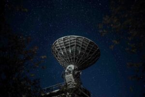 Telescópio apontado para o céu noturno captando astronautas na Lua.