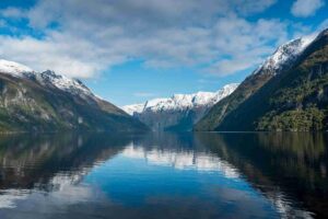 Fjord estreita com água agitada entre encostas rochosas cobertas de neve